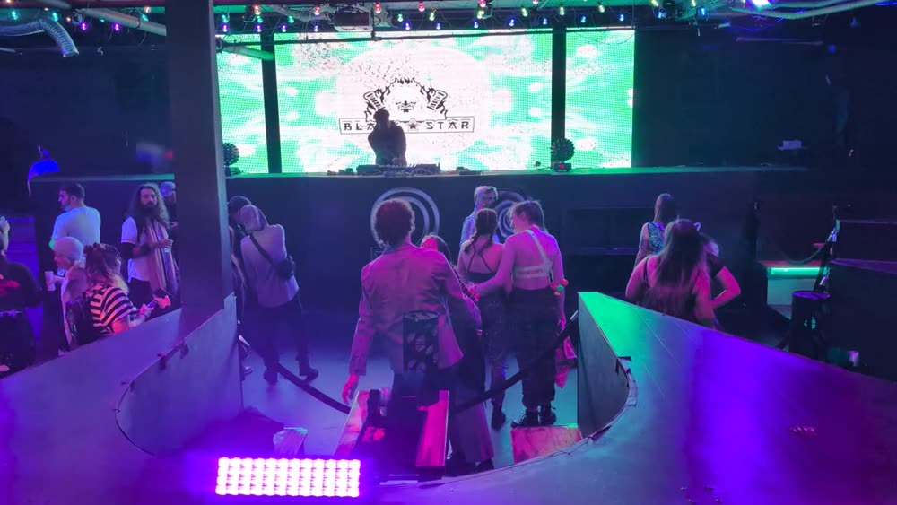 Club dance floor with a green LED wall behind the DJ