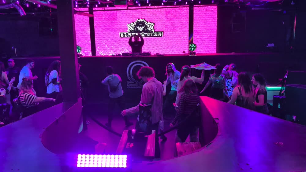 Club dance floor with a magenta LED wall behind the DJ