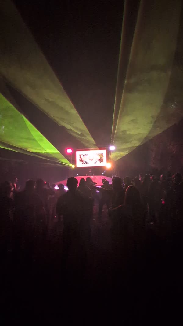Green lasers fanning over a festival crowd at night