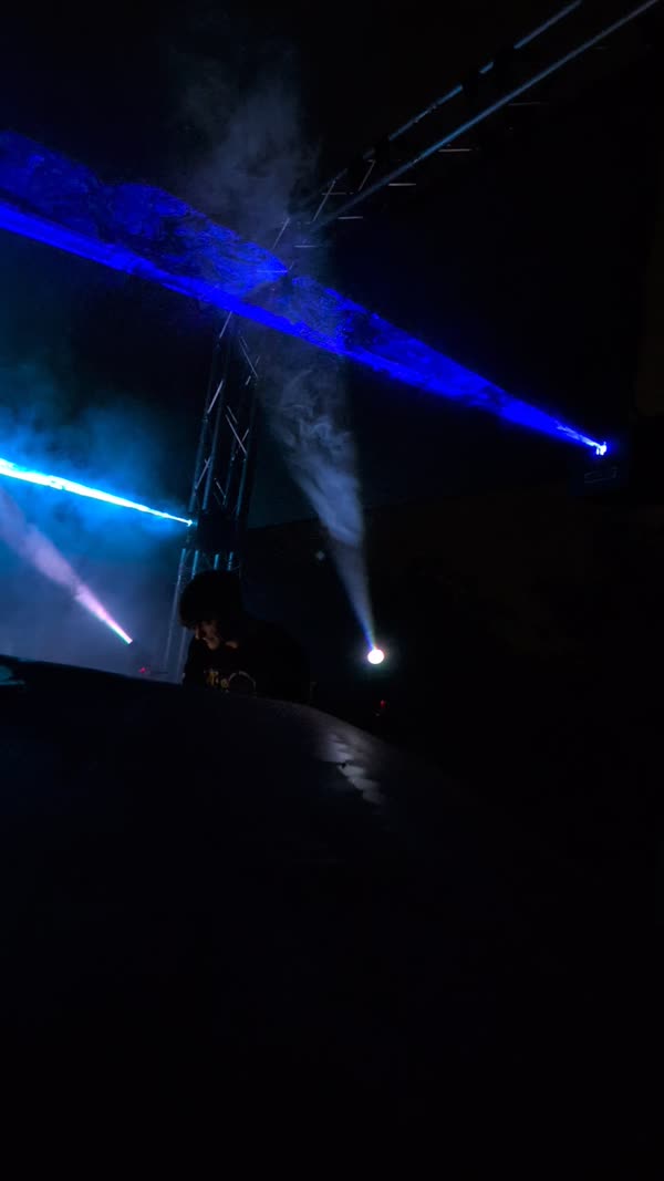 Blue light beams cutting through haze from a truss